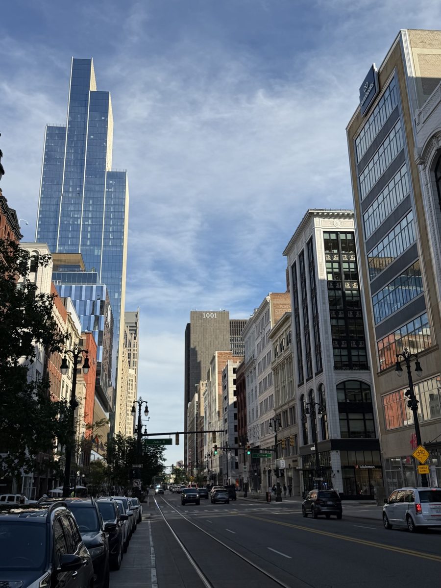 A downtown street with a glass tower on the left and historic buildings on the right, all leaning inward