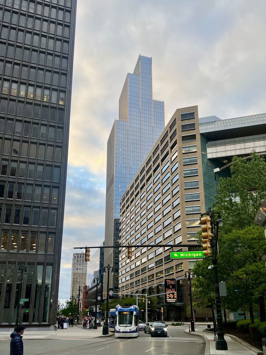 A glass office tower rising behind a brick building at a downtown intersection, converging toward the top