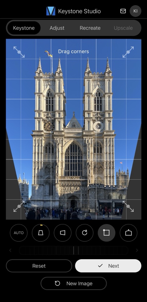 The corrected image shown as a trapezoid with empty dark wedges at each corner, with drag handles to fine-tune the corners